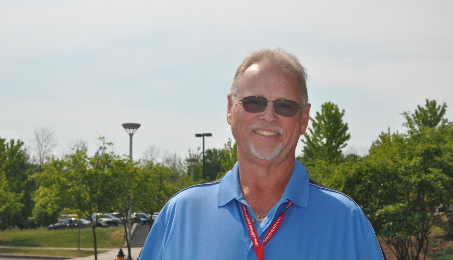 a man standing outside on a sunny day wearing a blue shirt and sun glasses 