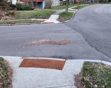 A sidewalk leading into the street but there is nota dedicated crosswalk