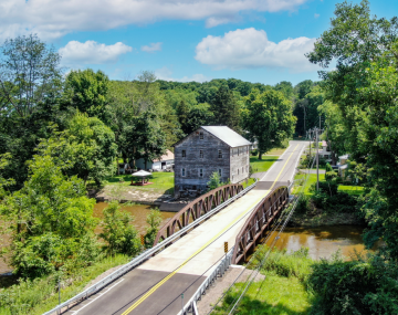 A road over a river that passes next to a house